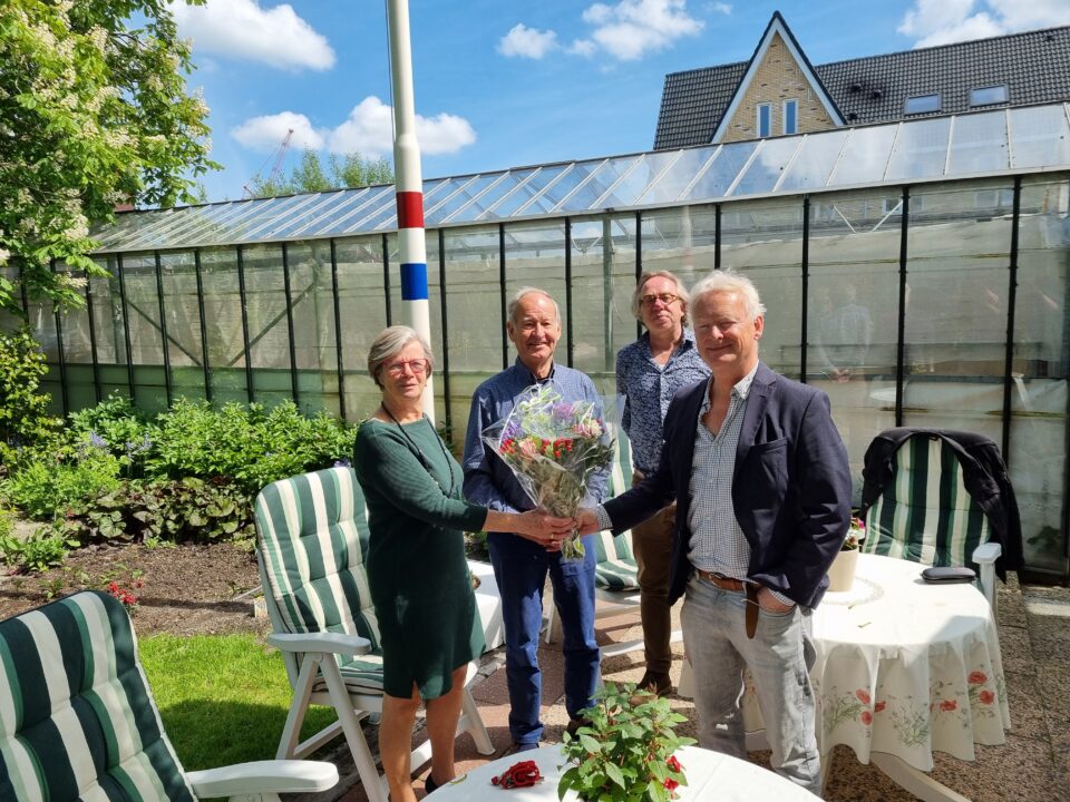 Voorzitter Lucas van Wees overhandigt Aad en Toni van der Meer de bloemen. Op de achtergrond Jan van der Mast.